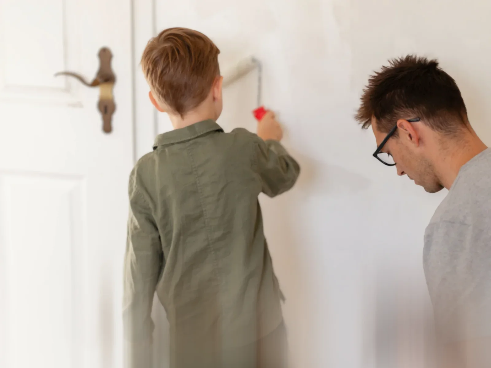 A young boy applying paint to a wall